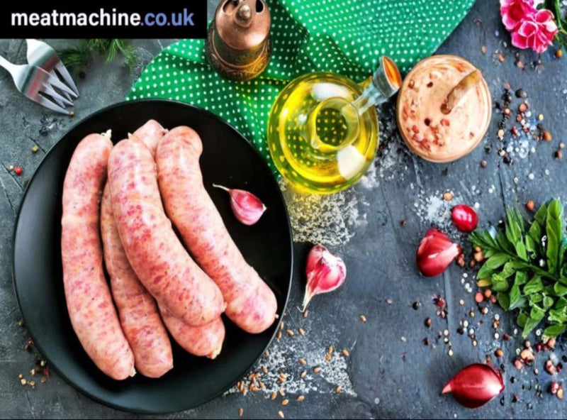 Raw sausages on a black plate with oil, herbs, and spices on a dark surface.