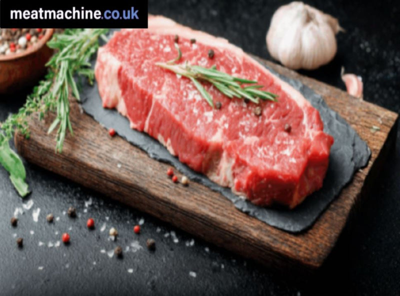 Raw steak on a wooden board with herbs and spices, branded 'meatmachine.co.uk'.