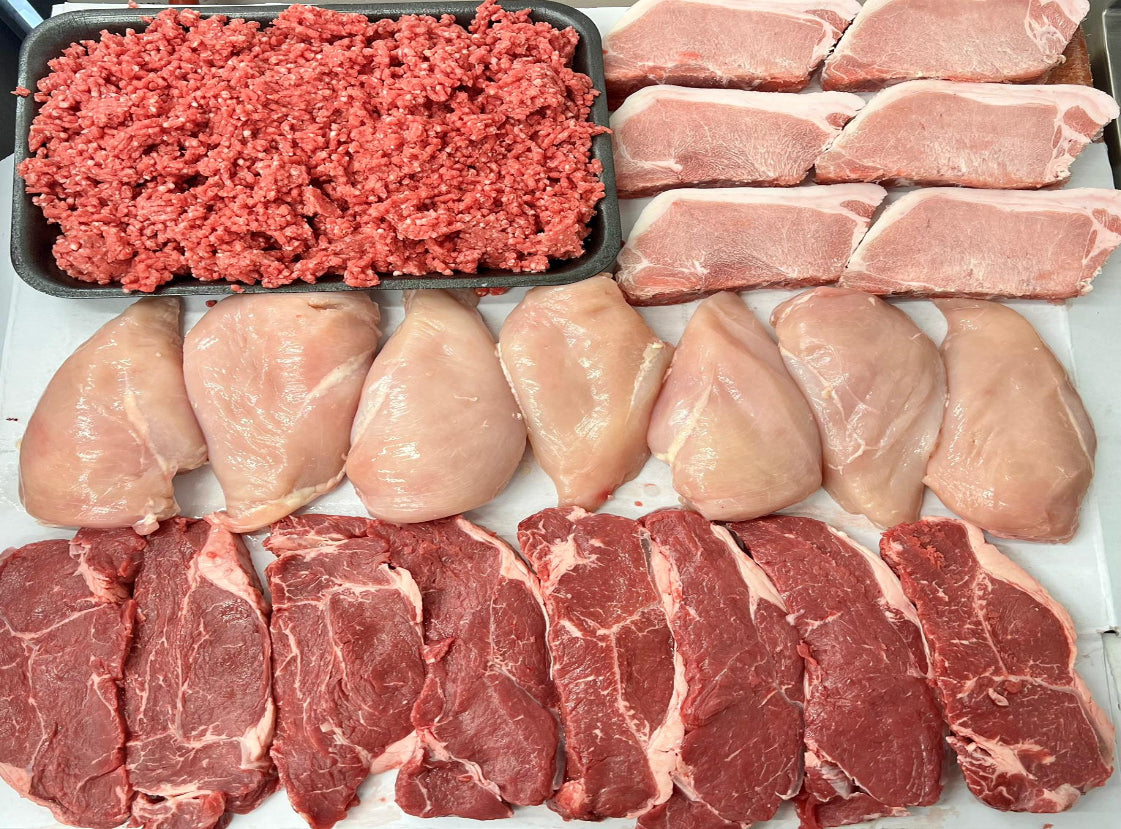 Assorted fresh meats including sirloin steak, lean steak mince, chicken breast fillets, and pork loin steaks arranged on a table.